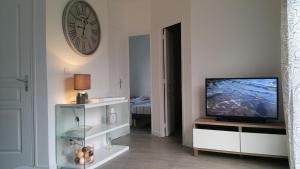 a living room with a television and a clock on the wall at Cottage sword beach in Hermanville-sur-Mer