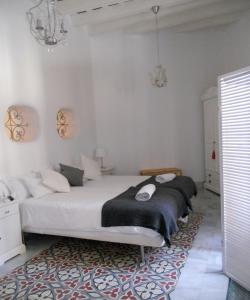 1 dormitorio con cama blanca y manta negra en Santa María 12 Boutique Apartamentos en Cádiz