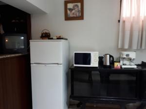 a kitchen with a refrigerator and a table with a microwave at Residencial Coroa D'Ouro in Fátima
