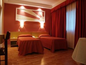 two beds in a hotel room with red walls at Hotel El Cabildo in Buenos Aires