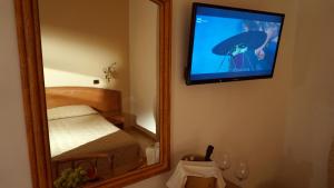 a bedroom with a mirror and a television on a wall at Hotel Portonuovo in Vieste