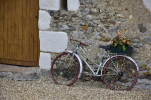 a bike parked against a stone wall with flowers in a basket at La Tale in Chahaignes