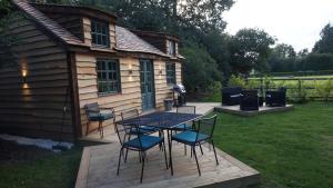 una casa y un patio con mesa y sillas en The Secret Cottage & Hideaway Caravan en Cudham