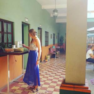 Hierba De Conejo Hostel في مدينة أواكساكا: امرأة ترتدي ثوب أزرق تقف في غرفة
