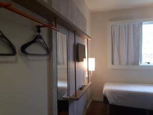 a hotel room with a bed and a window at ibis budget Barbacena in Barbacena