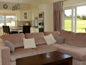a living room with a brown couch and a kitchen at Rivers Bend Cottage in Skull