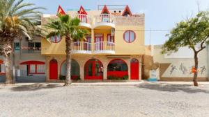 a large building with red doors and palm trees at Holiday ApartHotel in Santa Maria