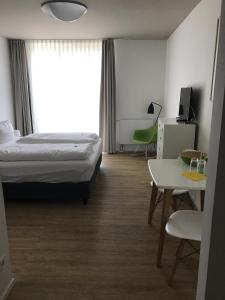 a hotel room with a bed and a desk and a table at Country Inn Suitenhotel in Werder