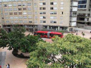 un autobus rosso parcheggiato di fronte a un edificio di Hotel San Sebastian a Bogotá