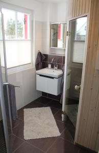 ein Bad mit einem Waschbecken und einem Spiegel in der Unterkunft Fischer's Ferienhaus Rügen mit Sauna und Kamin in Ummanz