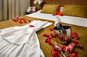 Villa Park Hotel في ناتال: سرير مع زجاجة من النبيذ وورد احمر عليه