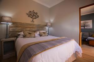 a bedroom with a large bed with a wooden headboard at Treehouse at Theebos in Strand