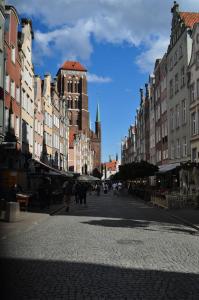 a city street with buildings and people walking down the street at Tawerna Rybaki Old Town in Gdańsk