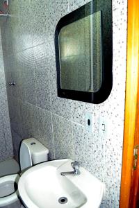 a bathroom with a sink and a mirror and a toilet at Hotel Pousa La in Cosmópolis