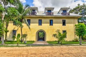 an old yellow house with palm trees in front of it at Toucan Suite @ Mahogany Hall in San Ignacio