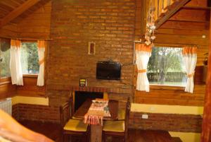a room with a fireplace and a table and a tv at Arroyo Escondido in Trevelín