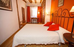 a bedroom with a large bed with two red pillows at El Bulín de Pedraza - Casa del Serrador in Pedraza-Segovia