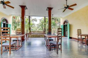 a dining room with tables and chairs and windows at Family Suite @ Mahogany Hall in San Ignacio