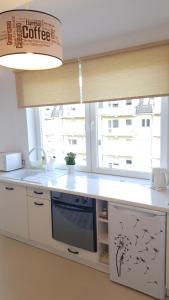 a kitchen with a white counter with a window at Apartament Muszelka in Ustka
