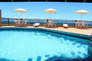 a swimming pool with chairs and umbrellas at Pousada Ilha Bella in Guriri +19 photos
