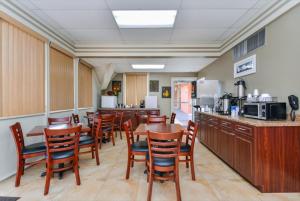 Americas Best Value Inn Sarasota في ساراسوتا: مطعم بطاولات وكراسي خشبية ومطبخ