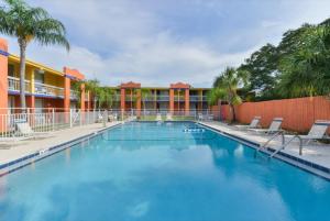 ein großer Pool mit Stühlen und ein Gebäude in der Unterkunft Americas Best Value Inn Sarasota in Sarasota