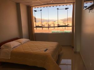 1 dormitorio con cama y ventana grande en Edmoli Casa Hospedaje, en Cusco