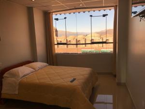 ein Schlafzimmer mit einem Bett und einem großen Fenster in der Unterkunft Edmoli Casa Hospedaje in Cusco