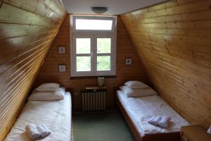 Duas camas num pequeno quarto com uma janela em Planinska vikendica LUCIJA em Fužine