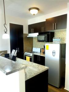 a kitchen with a white refrigerator and black cabinets at Apartamentos EcoVivienda in Tegucigalpa
