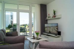 ein Wohnzimmer mit einem Sofa und einem TV in der Unterkunft Südkap A-02 in Pelzerhaken