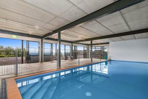 a large swimming pool with blue water in a building at Oreti Village Resort in Turangi