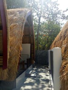 a building with a thatched roof with a pathway at Krisna Bungalows and Restaurant in Sekotong