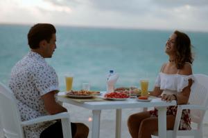 a man and a woman sitting at a table with food at Veli Thoddoo Inn in Thoddoo