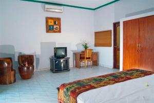 a hotel room with a bed and a television at Meriki Apartment in Seminyak