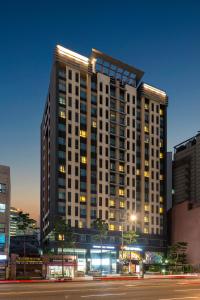 un edificio alto por la noche con una calle en Western Coop Hotel & Residence Dongdaemun, en Seúl