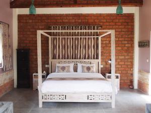a white bed in a room with a brick wall at Les Rizieres Lombok - Tetebatu in Tetebatu