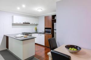 a kitchen with a stove, sink, and refrigerator at Oaks Brisbane Lexicon Suites in Brisbane
