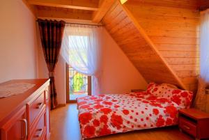 a bedroom with a red and white bed and a window at Apartament Dana in Poronin