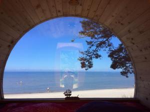 an arched window with a view of the beach at Kempings Saulesmājas in Kolka