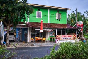 a green building with a table in front of it at Krui Saejadi Surf and Stay in Krui