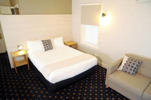 a hotel room with a bed and a chair at Sovereign Hill Hotel in Ballarat