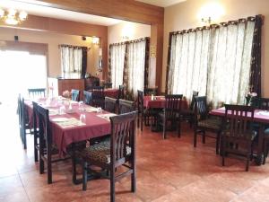 a dining room with tables and chairs with pink tablecloths at Berry Hills Resort in Ooty