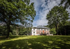 ein großes Haus auf einem grasbewachsenen Feld mit Bäumen in der Unterkunft Vila Na Landeku in Ostrava