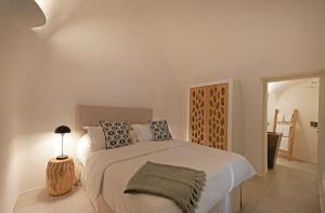 a bedroom with a large bed and a table with a lamp at Native Eco Villas in Imerovigli