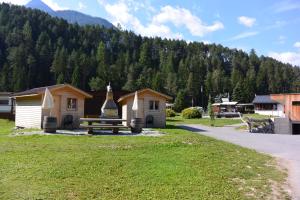 a group of small buildings in a field with a mountain at Camping Sur En in Sent