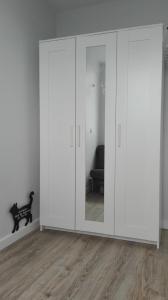 a large white closet with glass doors in a room at Apartament Maneki Neko in Wrocław