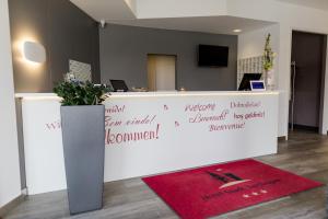 a reception desk in an office with a red rug at Hotel Stadt Tuttlingen in Tuttlingen