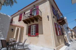 a building with chairs and a table in front of it at Pension Dafni in Nafplio