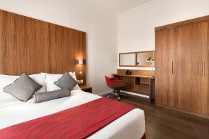 a hotel room with a large bed and a desk at Ramada Encore Al Khobar Olaya in Al Khobar